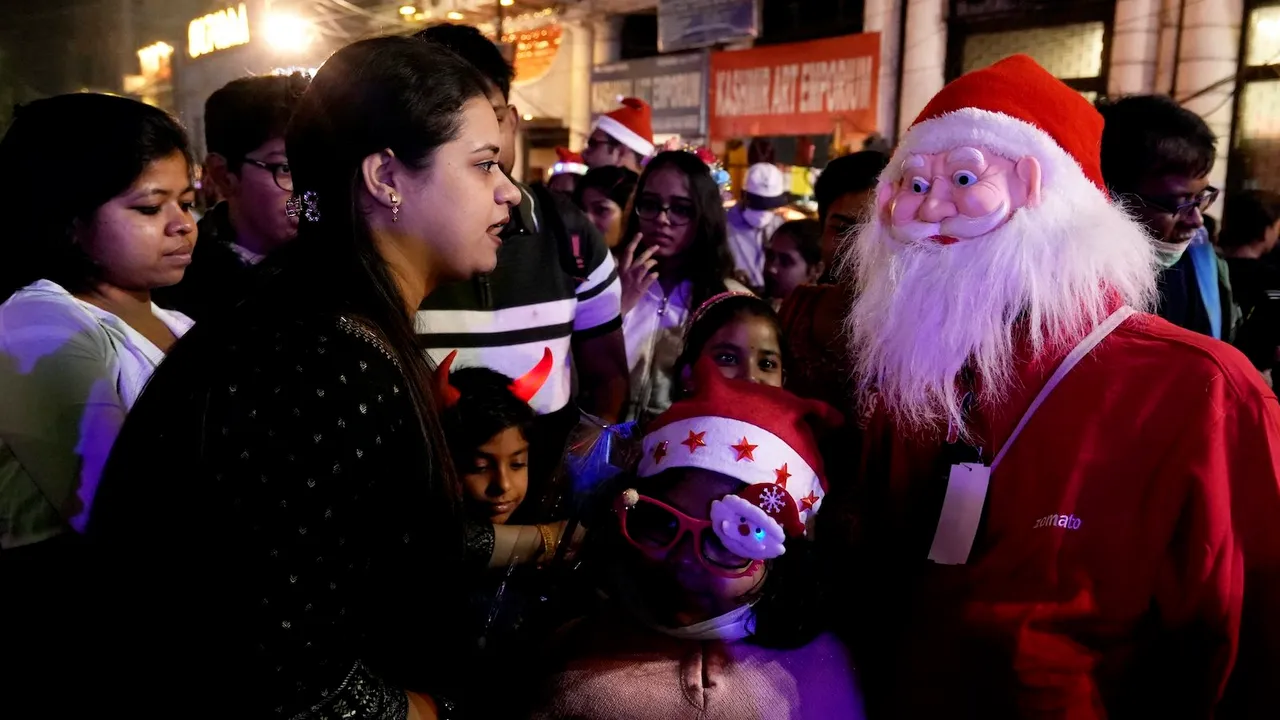 A man dressed as Santa Claus interacts with people at Park Street on the eve of Christmas Day celebrations, in Kolkata