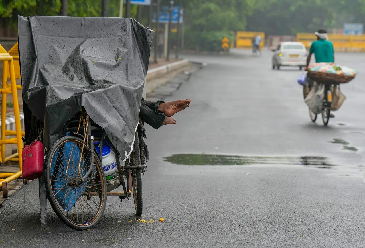 A person with disability rests at the side of a road on a rainy day as the southwest Monsoon advances over Delhi