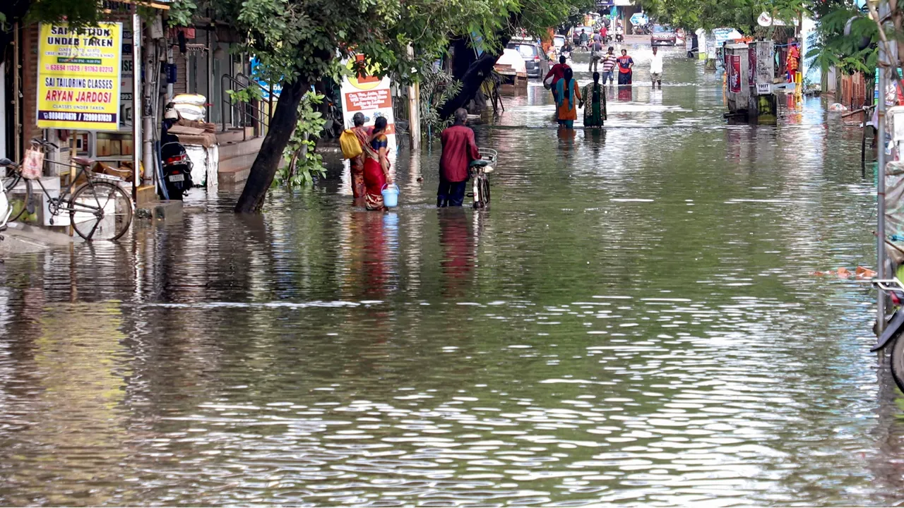 Locals wade through a waterlogged street after heavy rain, in Chennai