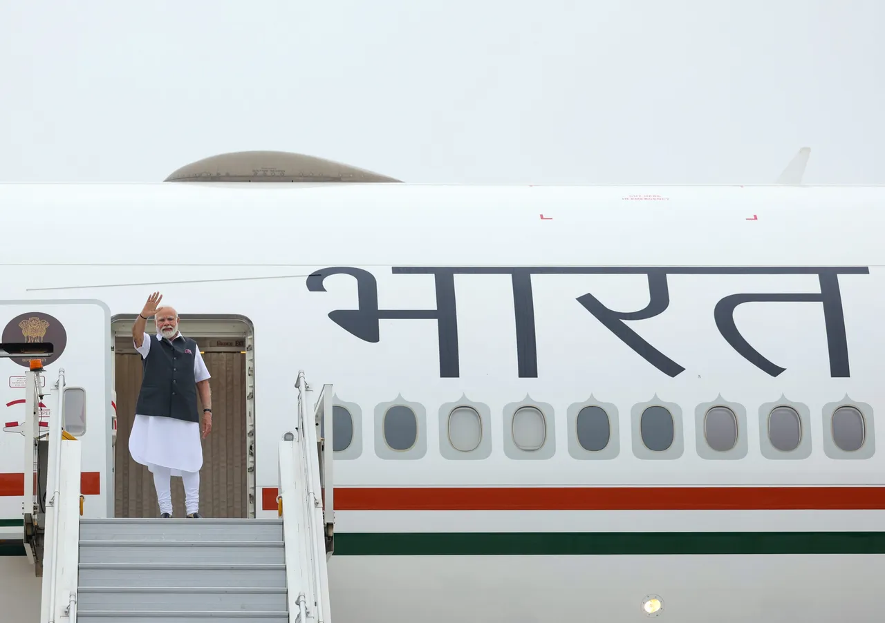 Prime Minister Narendra Modi waves while leaving for his visit to Paris, in New Delhi