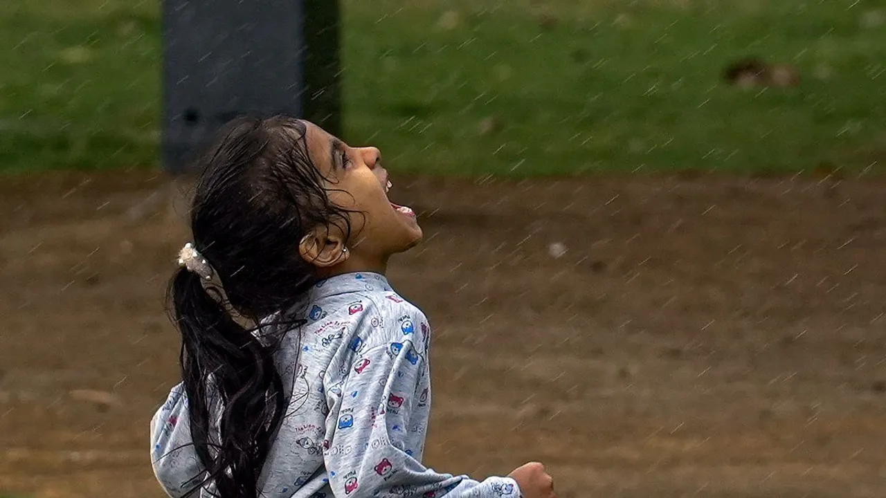 A young girl plays during rain, near India Gate, in New Delhi, Thursday, July 18, 2024