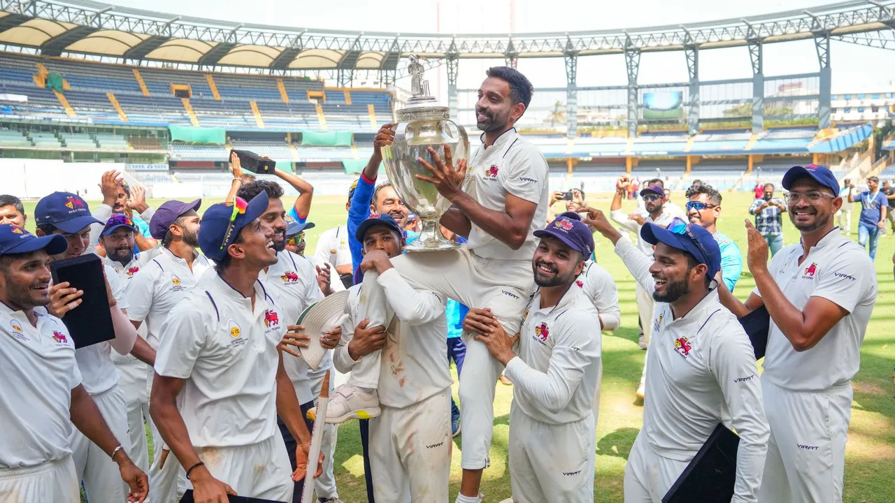 Mumbai's Dhawal Kulkarni lifts the championship trophy after winning the Ranji Trophy final