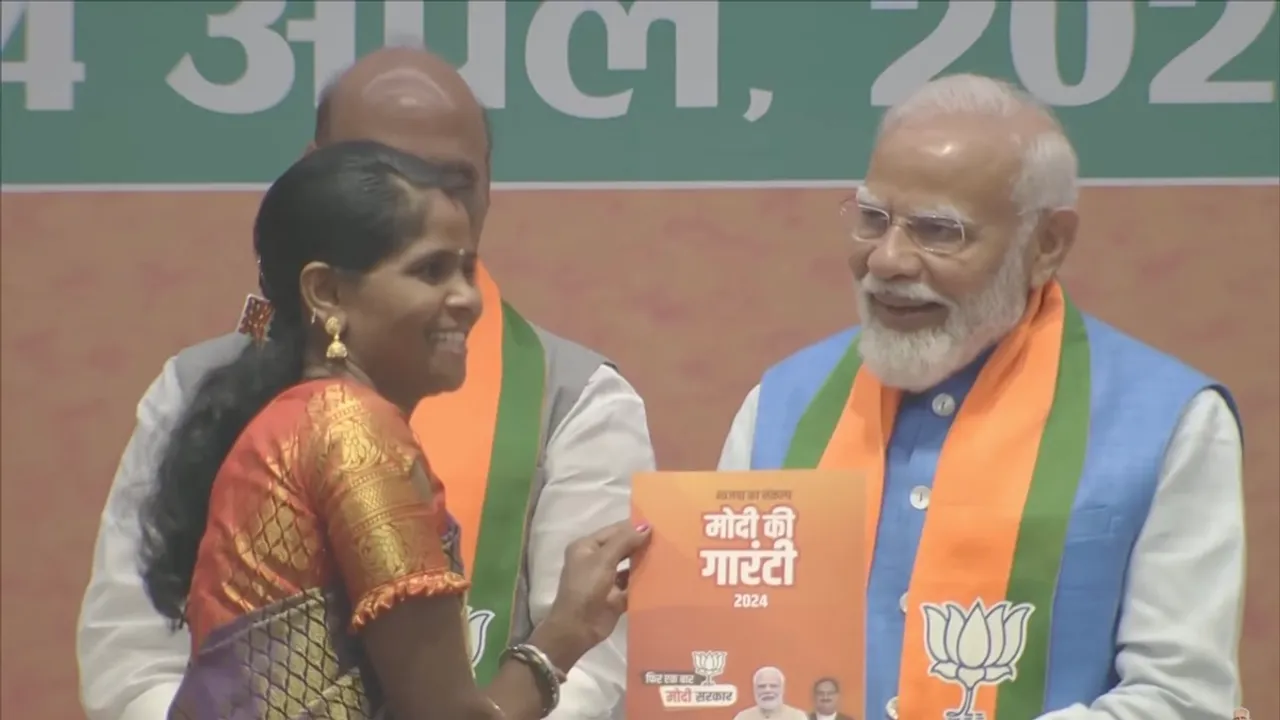 Narendra Modi hands over the BJP manifesto - Sankalp Patra - to a beneficiary of Ujjawala Yojana