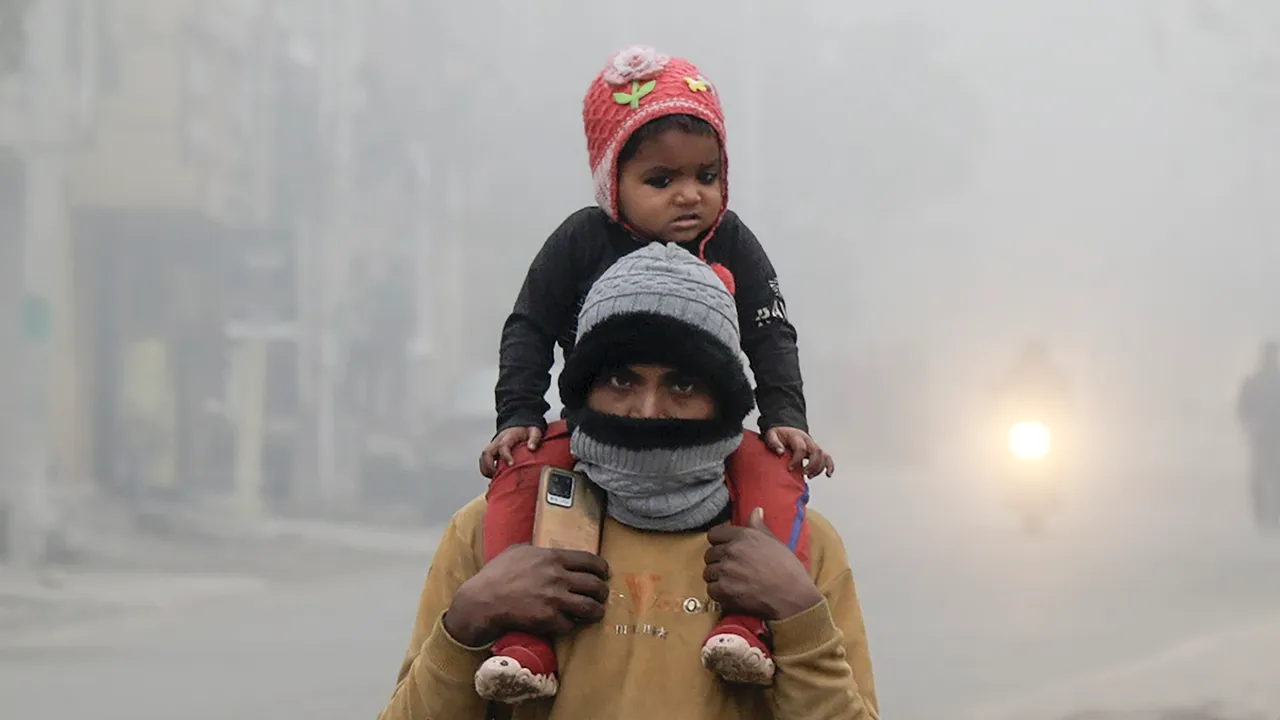 A man and a child walk by amid fog on a cold winter mornin