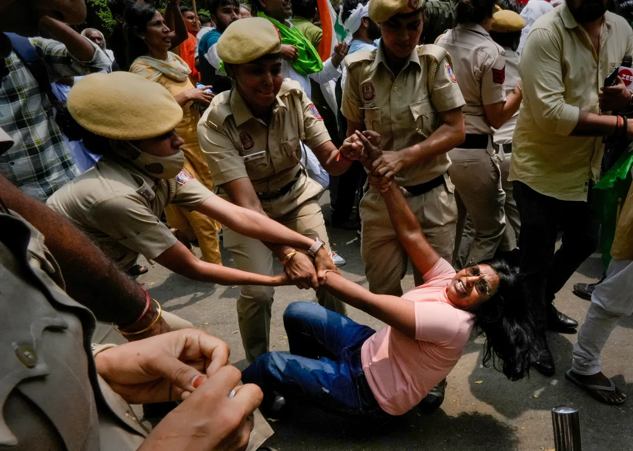 Police personnel detain an agitator during wrestlers' protest march towards new Parliament building, in New Delhi