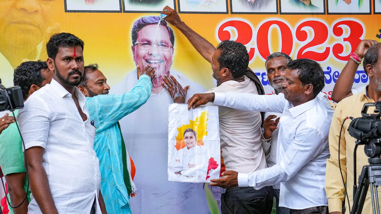 Supporters of Siddaramaiah perform 'abhishek' of his poster during celebrations outside his residence in Bengaluru on May 18
