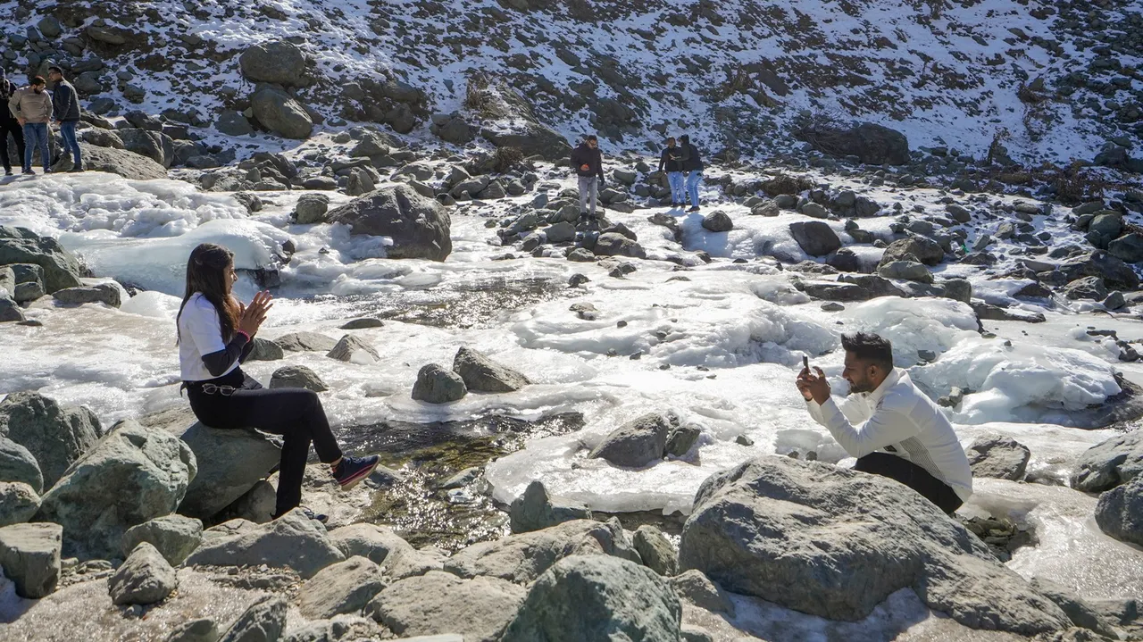 Tourists at a frozen stream, at Chandanwari in Anantnag district