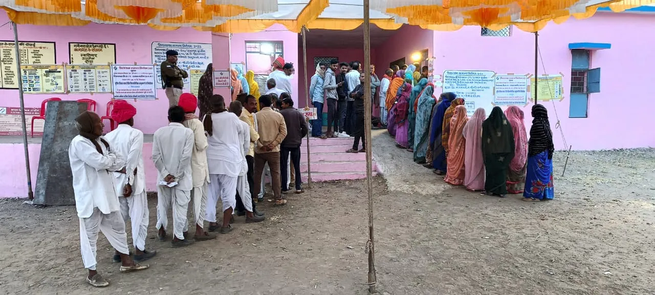 Voters wait in queues at a polling station to cast their votes for the Madhya Pradesh Assembly elections