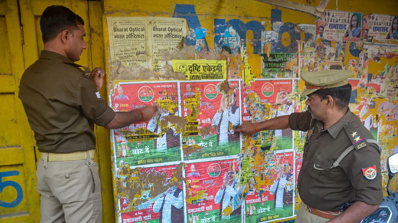 Police personnel remove posters of political leaders after the Model Code of Conduct was enforced following the announcement of the schedule of Lok Sabha elections, in Mirzapur