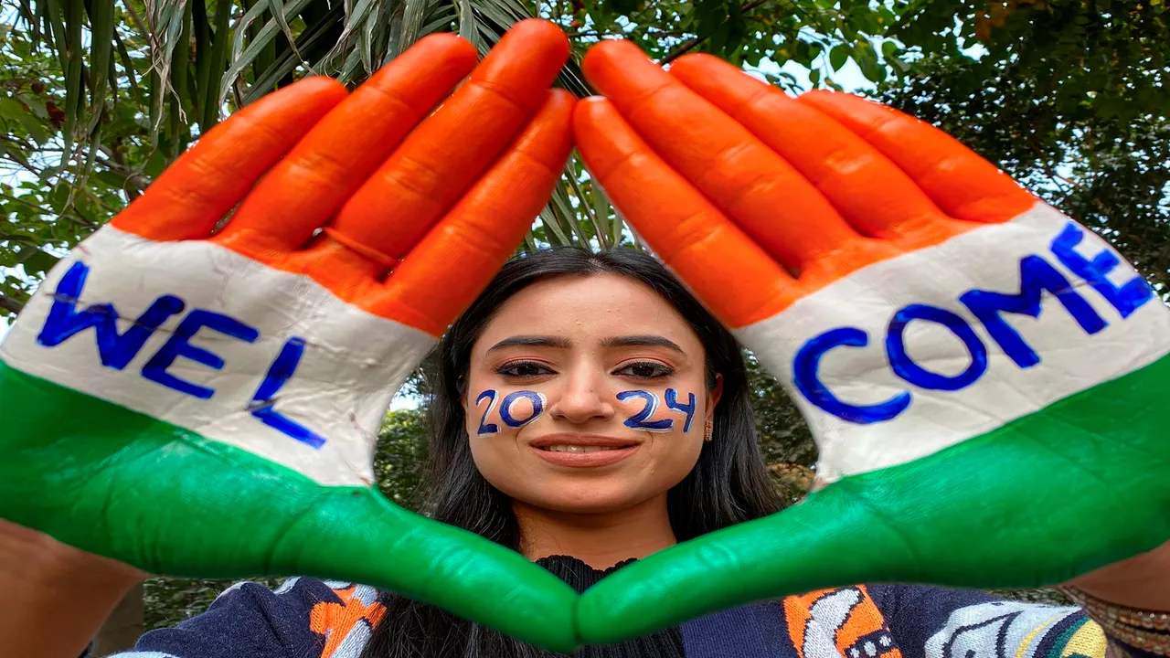 A woman with her face and palm painted in the Indian tricolour pose for photos ahead of the New Year, in Amritsar