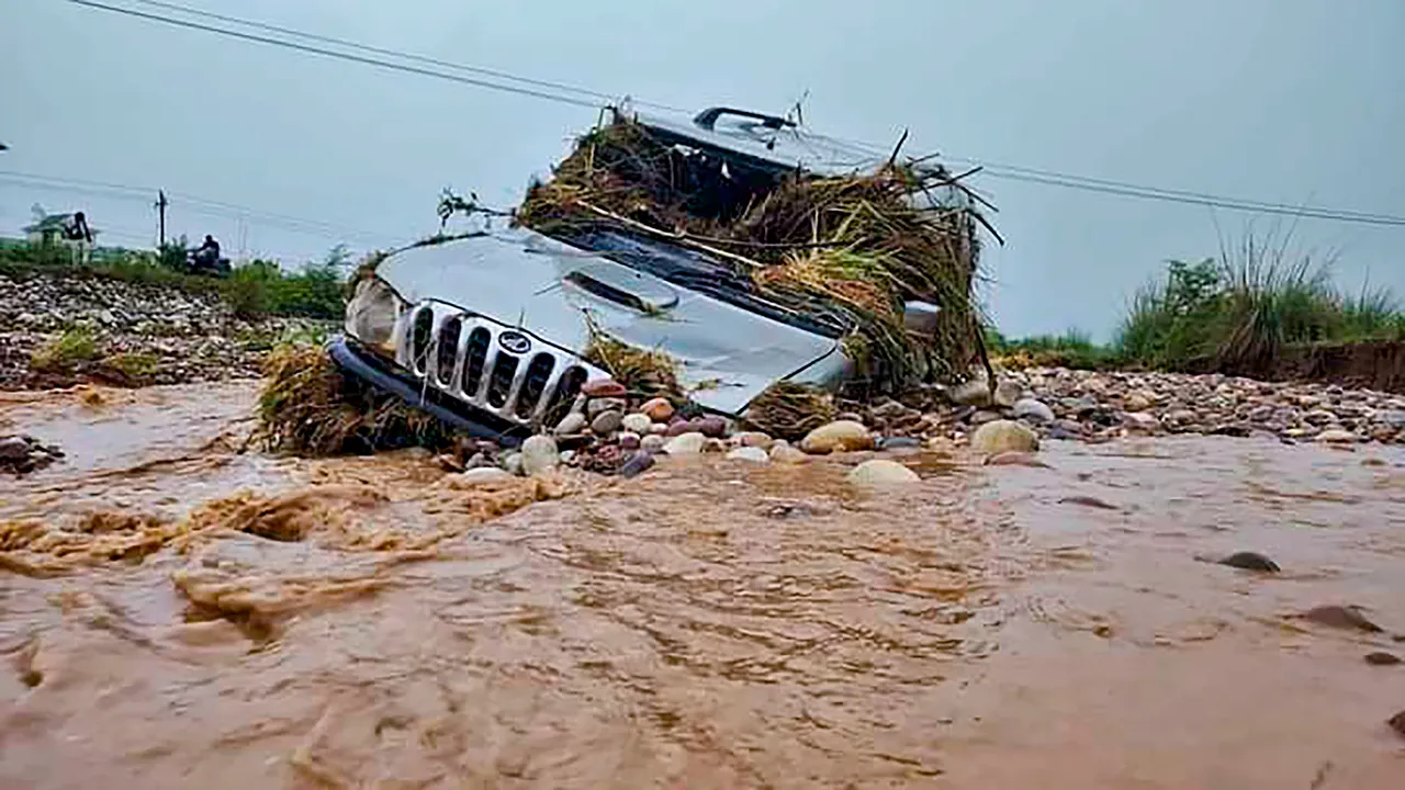 View of a car swept away in the water after flash floods occurred due to heavy monsoon rainfall, in Una district.jpg