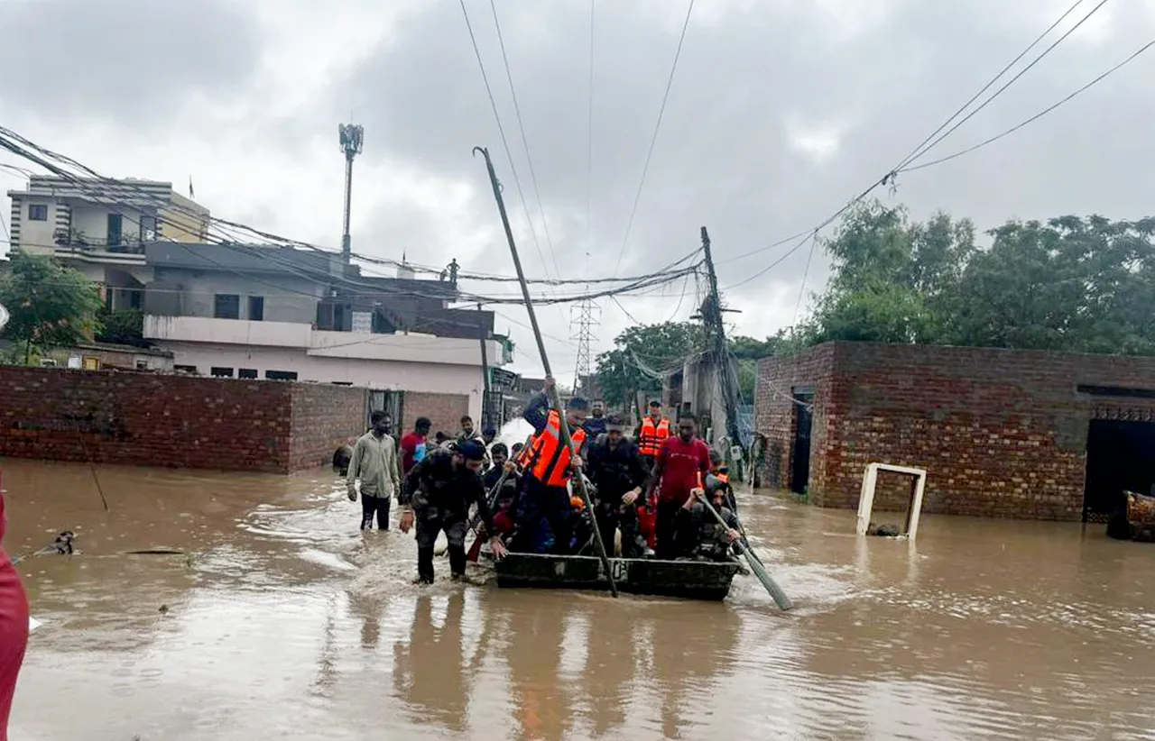 Rescue team members shift locals stuck near flooded Rishi Colony to a safer place after water level of Badi Nadi rose due to heavy monsoon rains, in Patiala