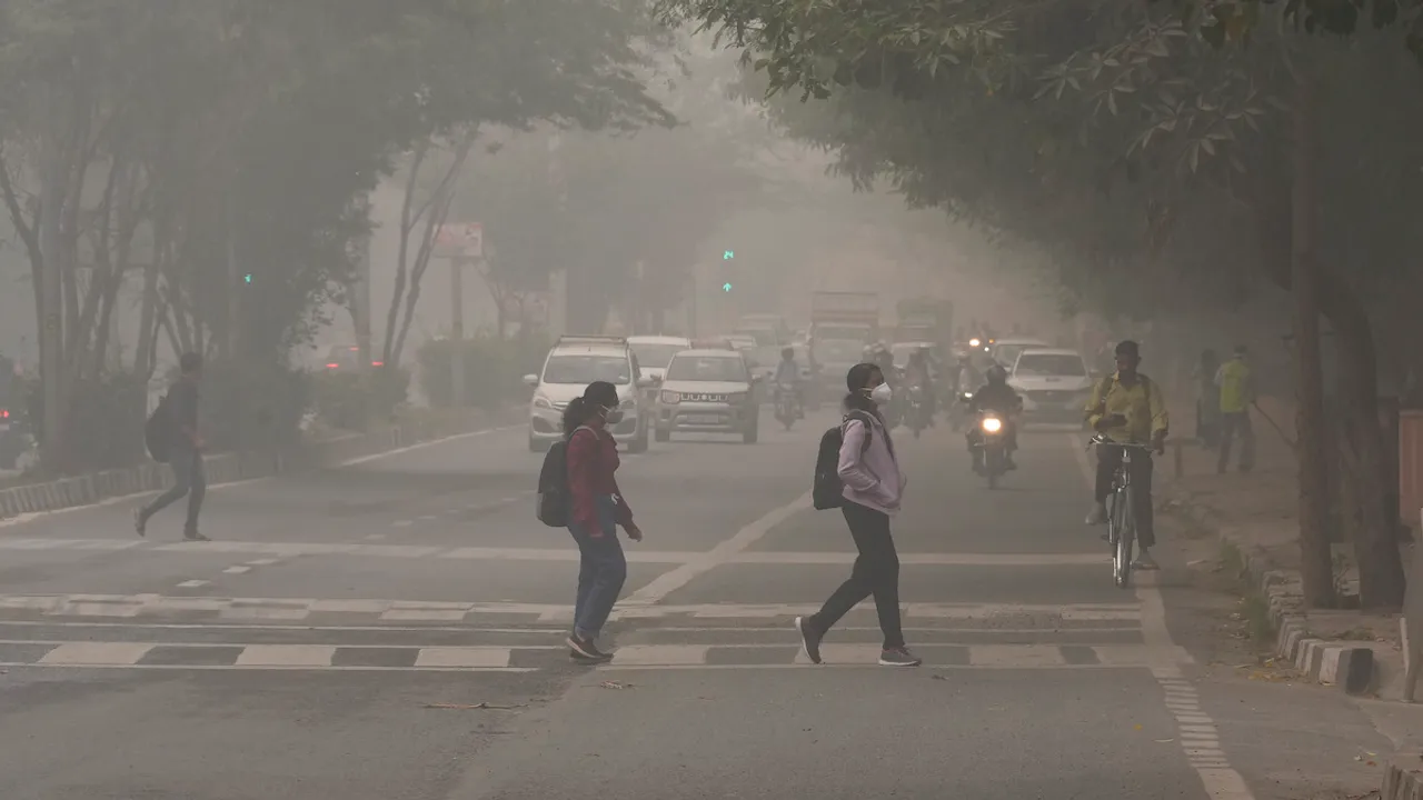 Students wearing anti-pollution masks cross a road amid hazy weather conditions, in New Delhi, Friday, Nov. 3, 2023.