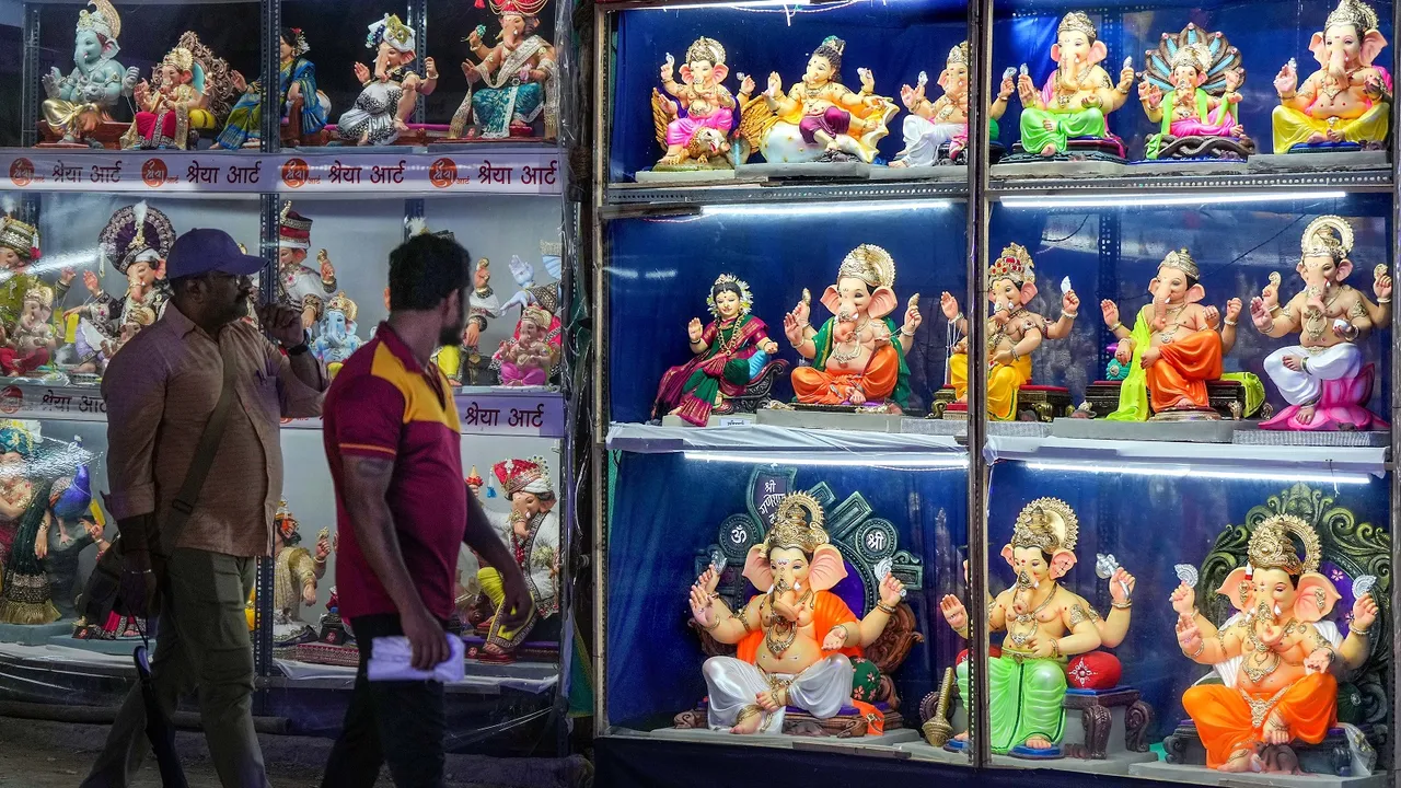 People walk past a display of Lord Ganesh idols at a workshop ahead of Ganesh Chaturthi festival, in Mumbai