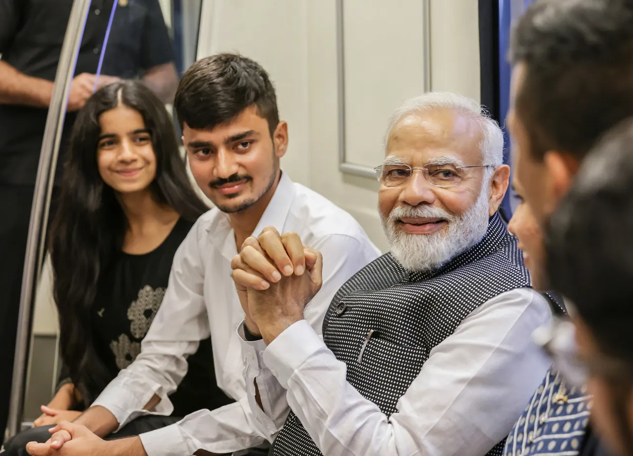 Prime Minister Narendra Modi interacts with passengers in Delhi Metro on his way to attend the centenary celebrations of the University of Delhi, in New Delhi, Friday