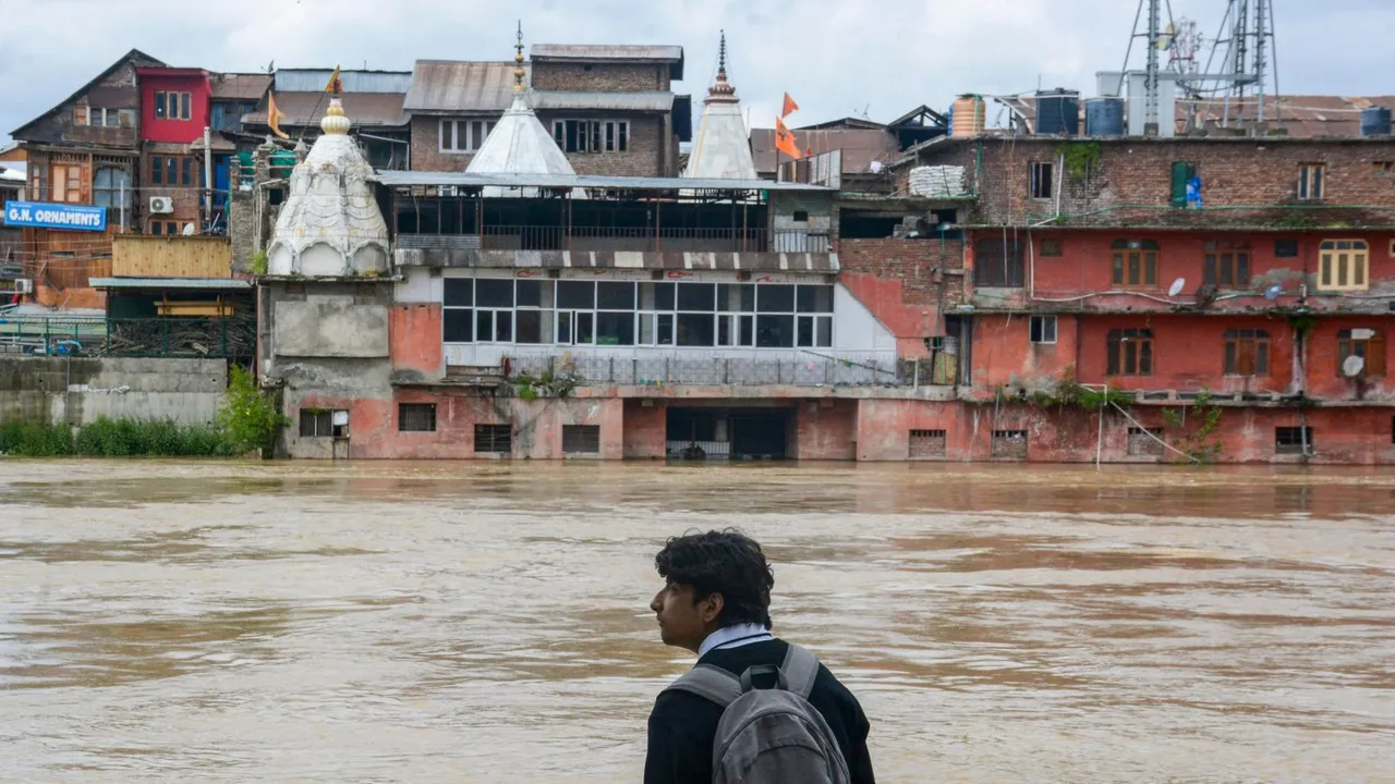 A youth looks on as the part of the Hanuman Mandir on the bank of Jhelum river is partially submerged under the flood water in Srinagar