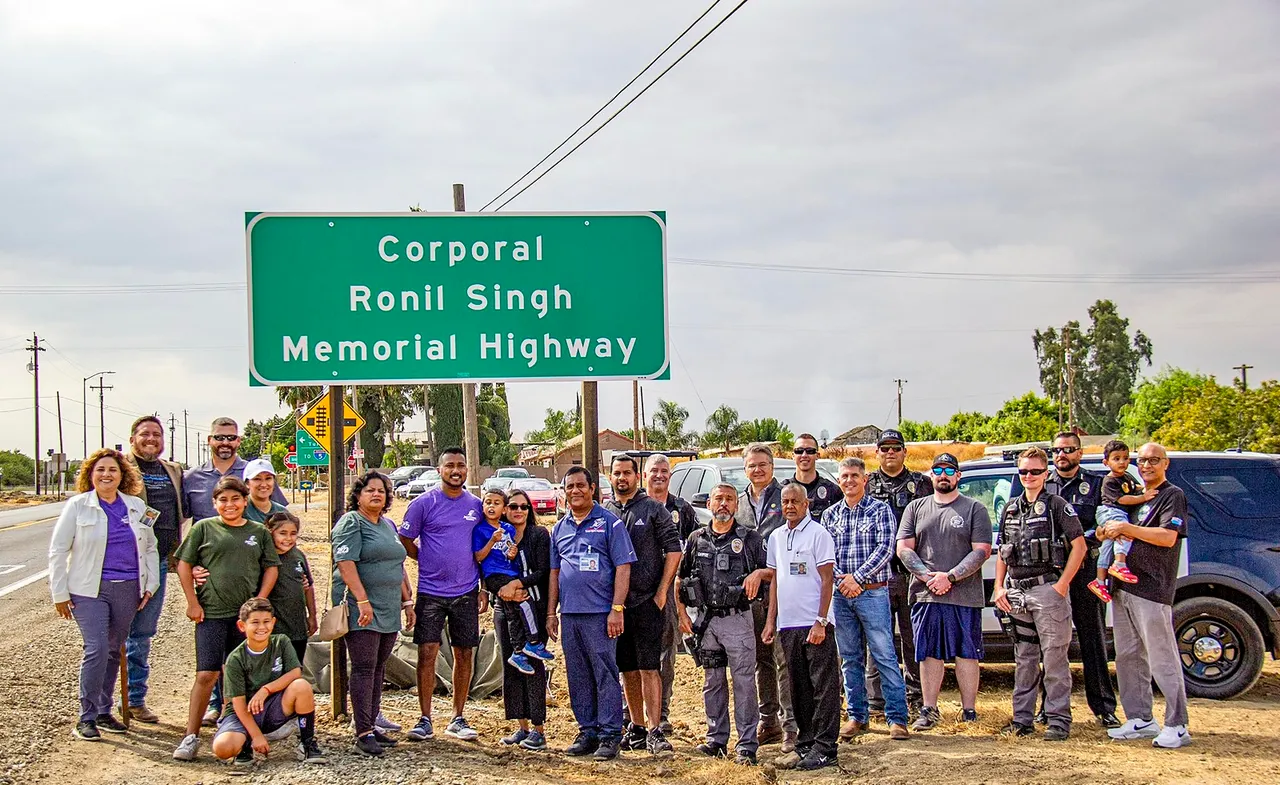 Family members and friends of an Indian-origin police officer pose for photos in front of a signage proclaiming the 'Corporal Ronil Singh Memorial Highway' in California, USA