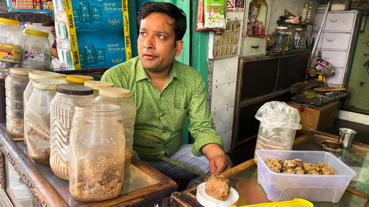 Lalit Vashney, a hing trader, interacts with a customer in Hathras