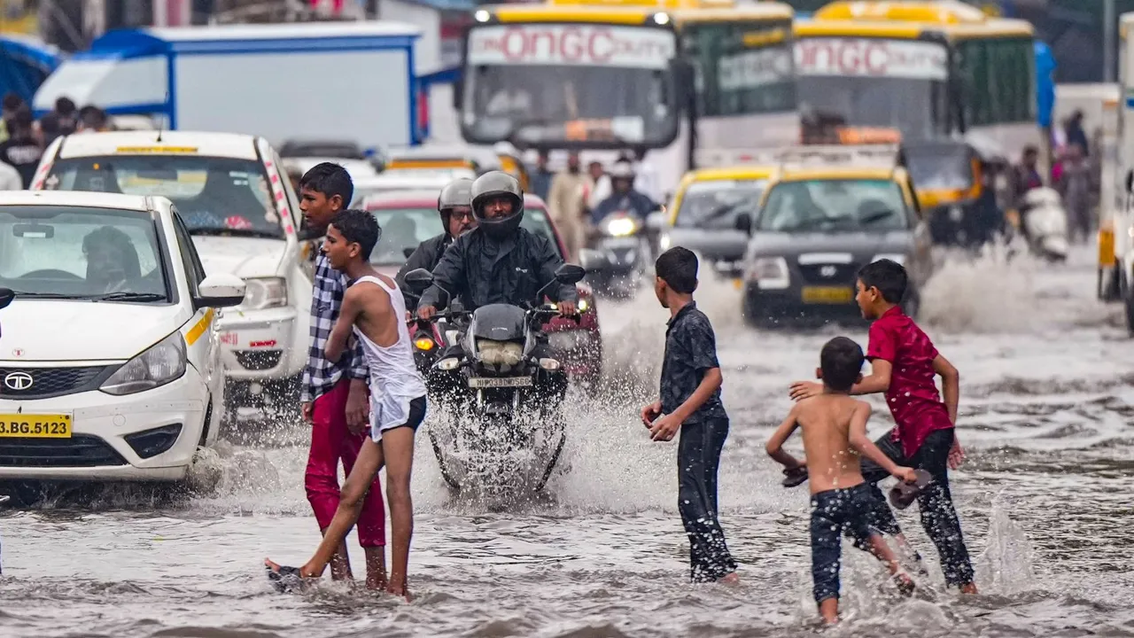 Commuters wade through a waterlogged street following rains, in Mumbai