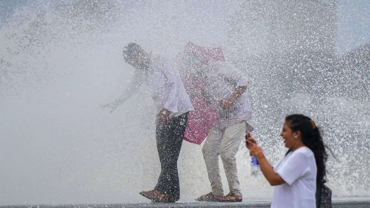 People enjoy as sea waves crash against the promenade during high tide, at Marine drive, in Mumbai, Wednesday, July 24, 2024.