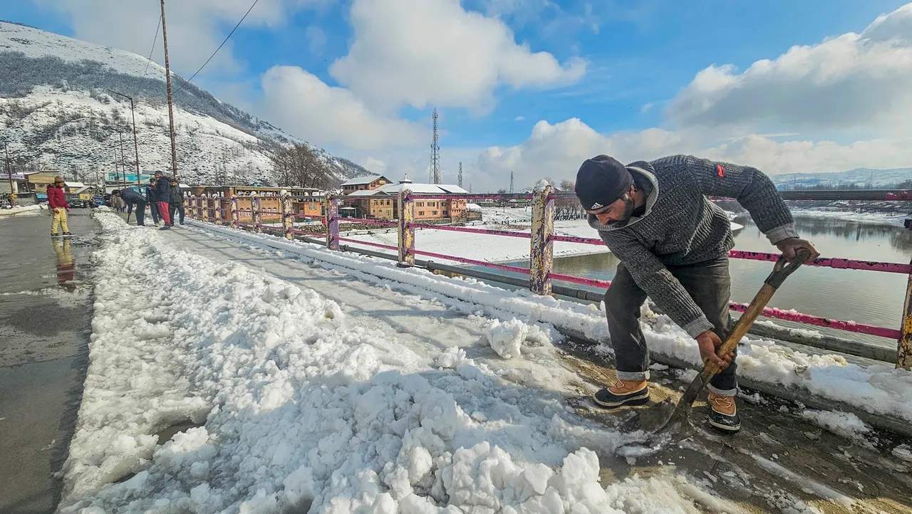 A worker clears snow from a road following fresh snowfall in Baramulla, Thursday, Feb. 1, 2024.