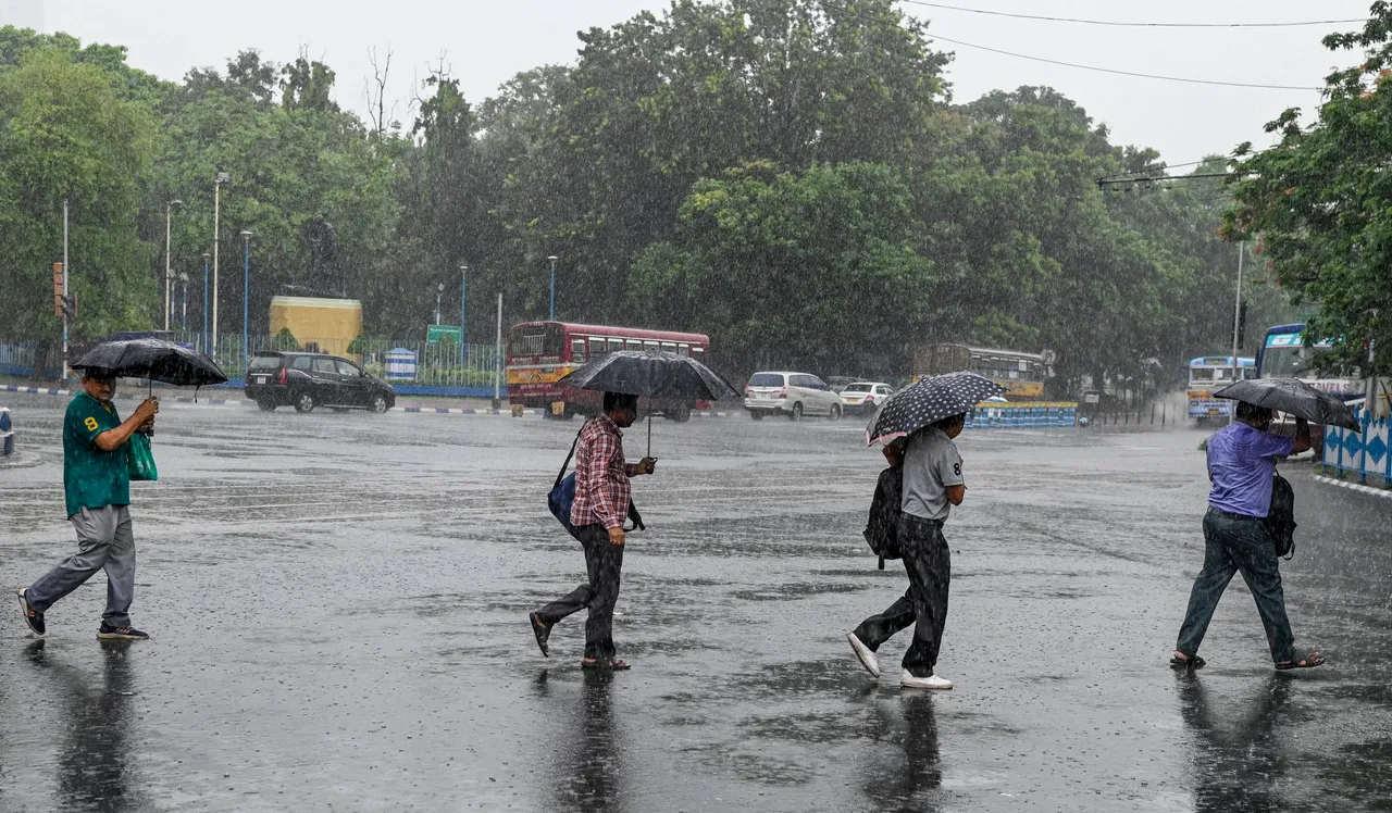 Pedestrians cross a road amid monsoon rain, in Kolkata