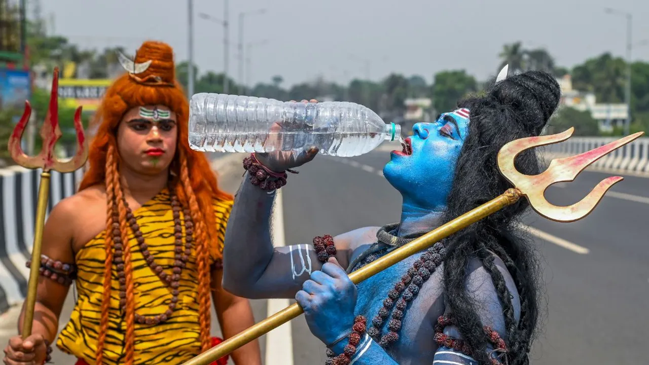 An artist dressed as Lord Shiva drinks water on a hot summer afternoon, in Nadia district, Friday, April 12, 2024
