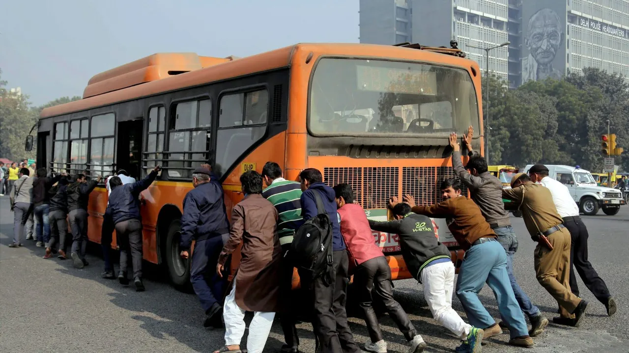 Passengers and traffic policemen push a bus after it broke down at a traffic intersection, in New Delhi