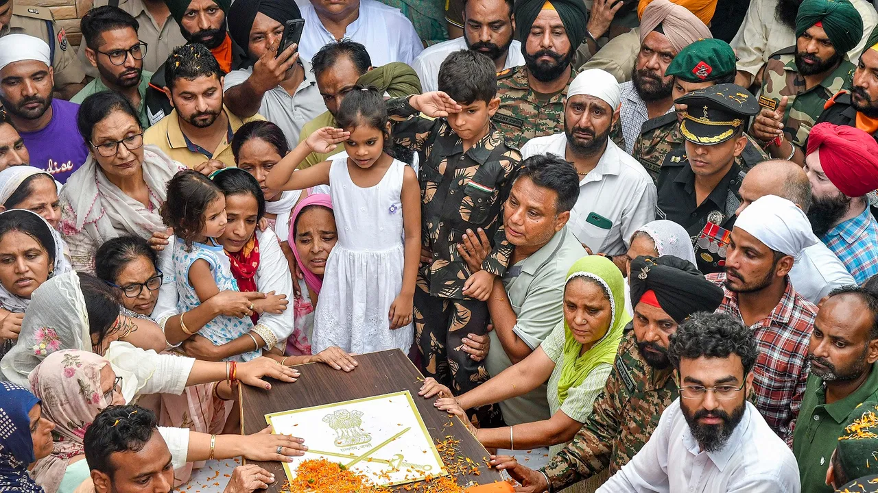 Son of Colonel Manpreet Singh salutes as family members and relatives mourn near his mortal remains before his last rites, at his native place in Mohali
