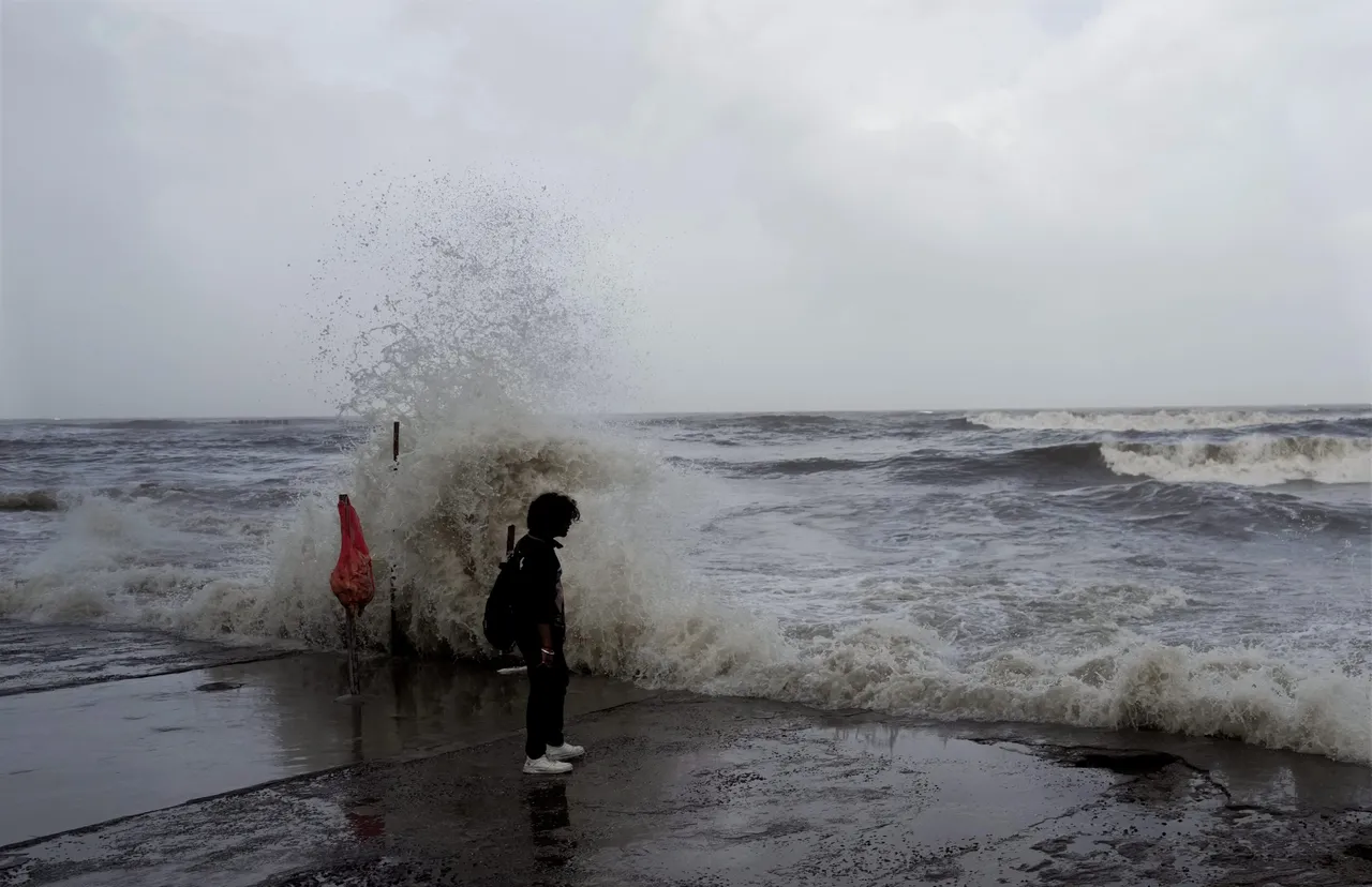 A man stands at Bandra beach while the high tidal waves lash the shore as the Biporjoy cyclone intensifies into a severe cyclonic storm, in Mumbai