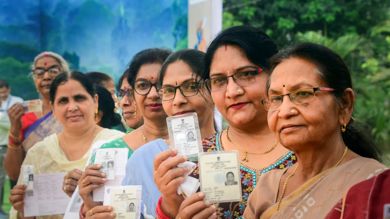 Voters show their identification cards as they wait in queues at a polling station to cast their votes for the first phase of Lok Sabha elections, in Bastar district, Friday, April 19, 2024