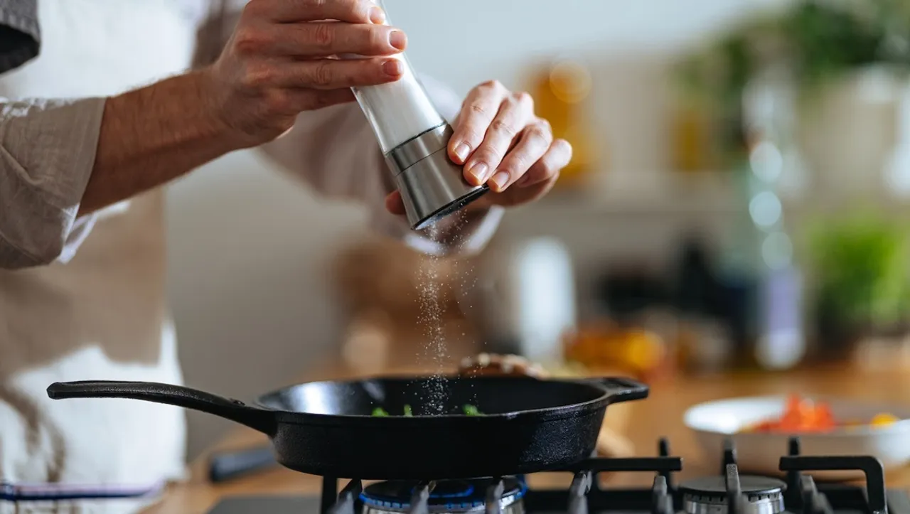 Man adding salt in an iron pan