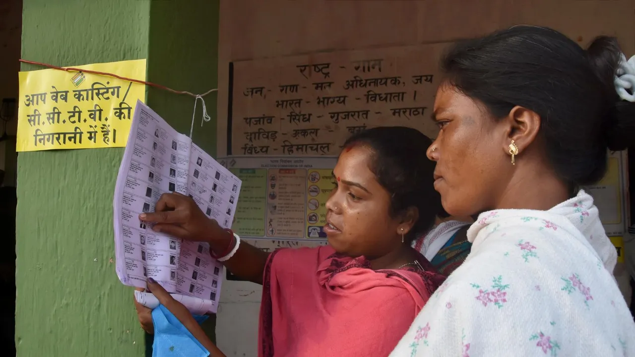 Woman voters search their names in voters' list at a polling station during fourth phase of Lok Sabha elections at Mandar, in Lohardaga district, Jharkhand, Monday, May 13, 2024