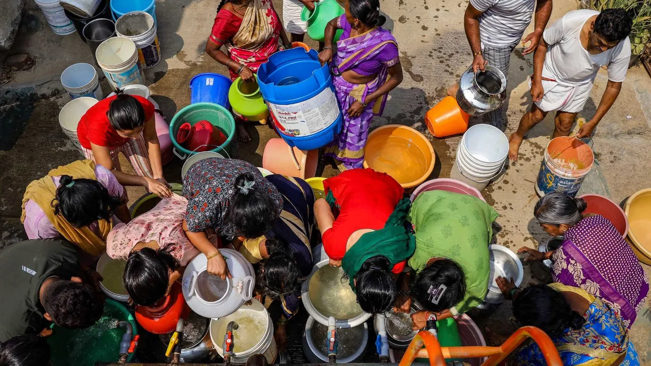 People collect free drinking water from a tanker due to water crisis at Bangarappa Nagar, in Bengaluru