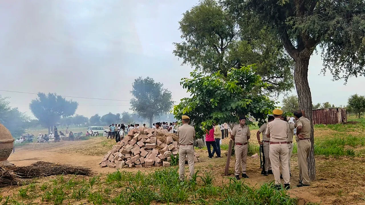 Police personnel investigate after charred bodies of four members of a family were found at their home, at Cherai village in Jodhpur district, Wednesday, July 19