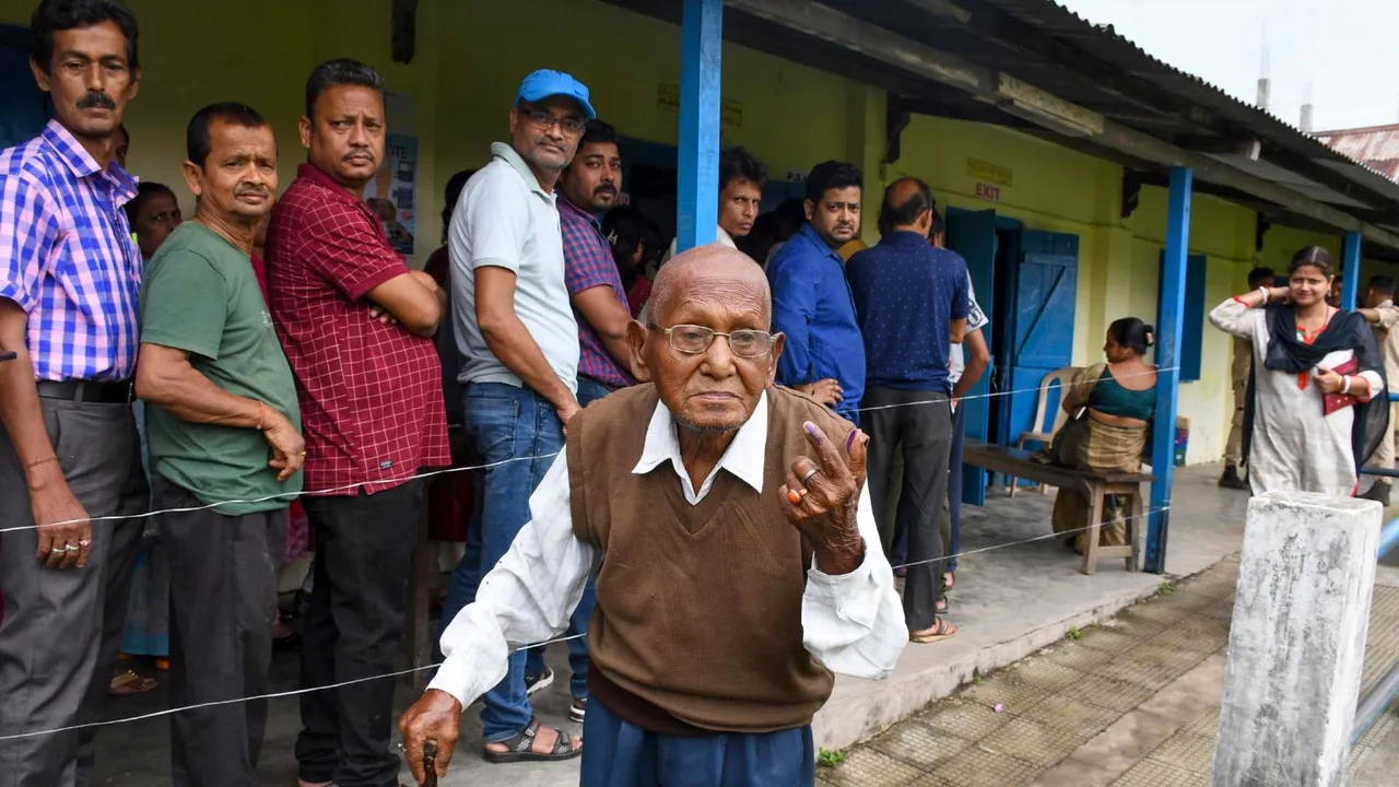 Voters show their identification cards as they wait in a queue at a polling station to cast their votes for the first phase of Lok Sabha elections, in Nagaon district, Friday, April 19, 2024