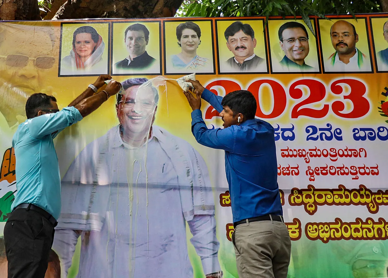 Supporters of Congress leader Siddaramaiah pour milk on his poster while demanding chief minister post for him, near his residence in Bengaluru