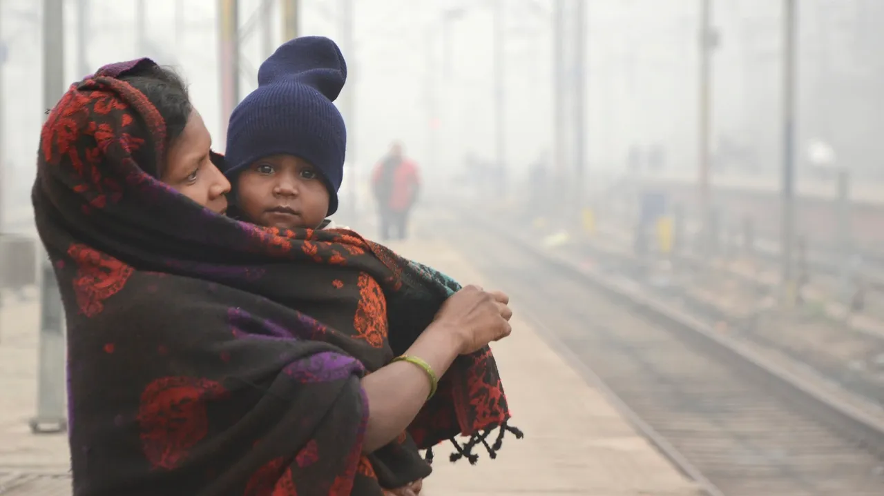 Passengers wait for a train at a railway station on a cold and foggy winter day, in Amritsar