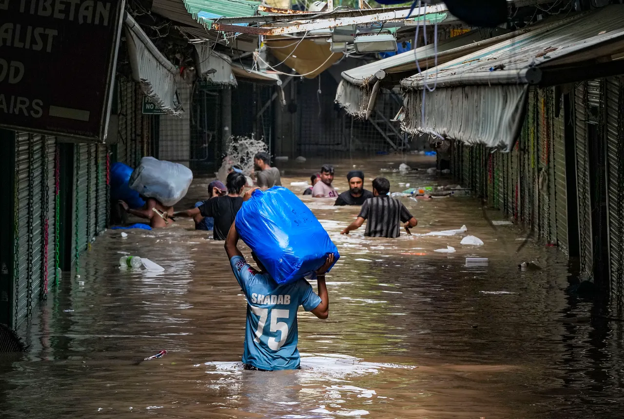 Locals wade through the flooded Monastery market following monsoon rains, in New Delhi