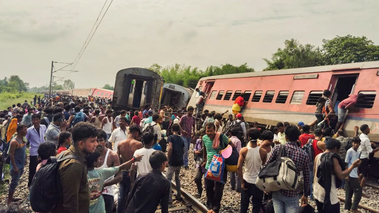 Passengers and locals near the derailed coaches of the Dibrugarh Express train after an accident, in Gonda district, Thursday, July 18, 2024.