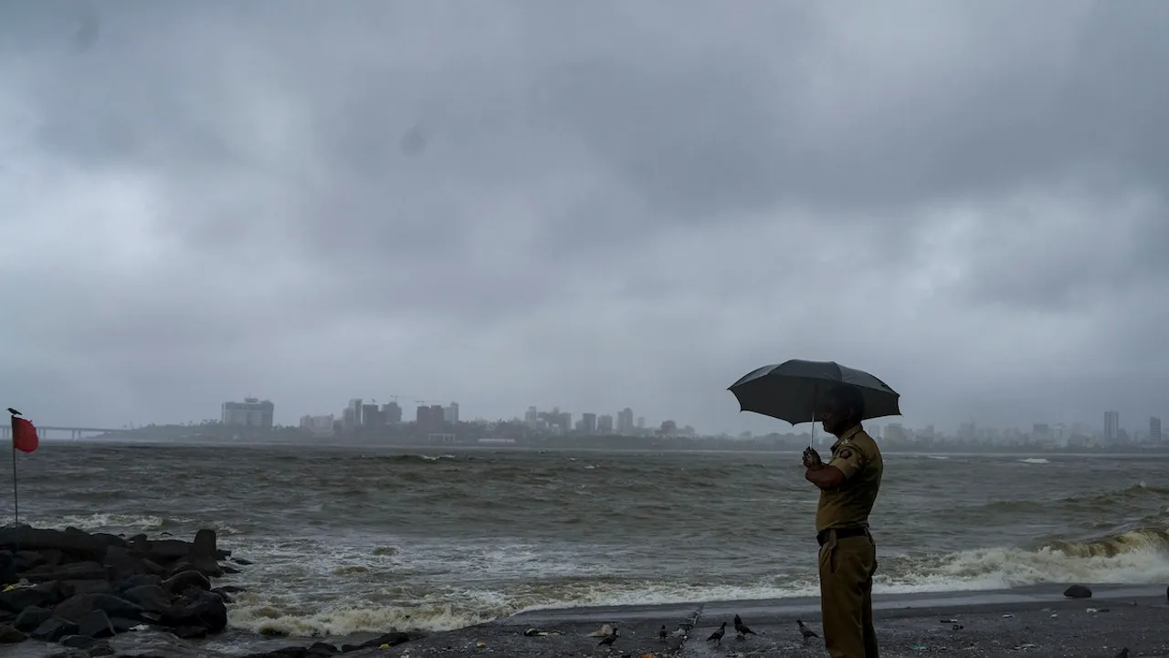 A police personnel stand guard at the coastline amid monsoon rains as high tidal waves crash at the shore, in Mumbai, Wednesday, July 19