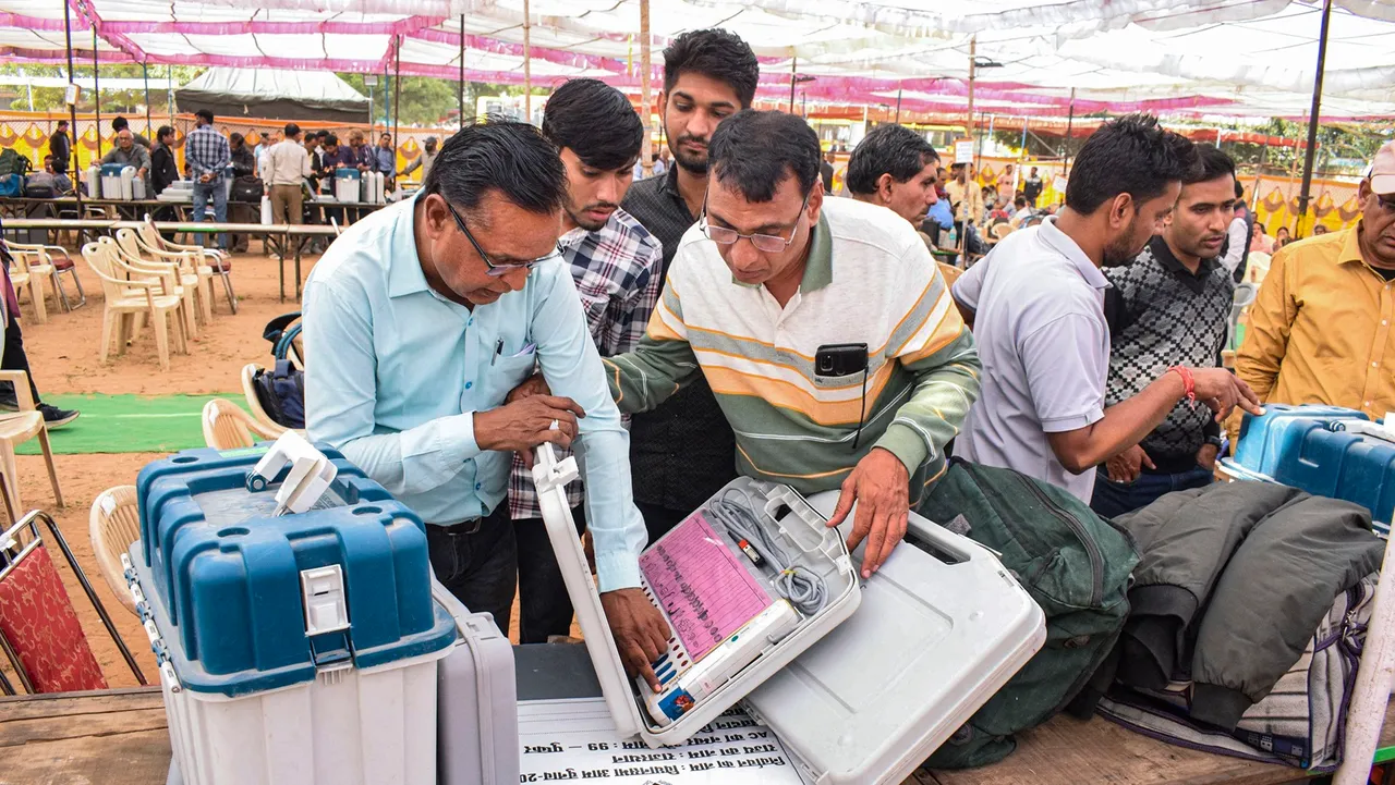 Polling officials collect EVMs and other election material at a distribution centre