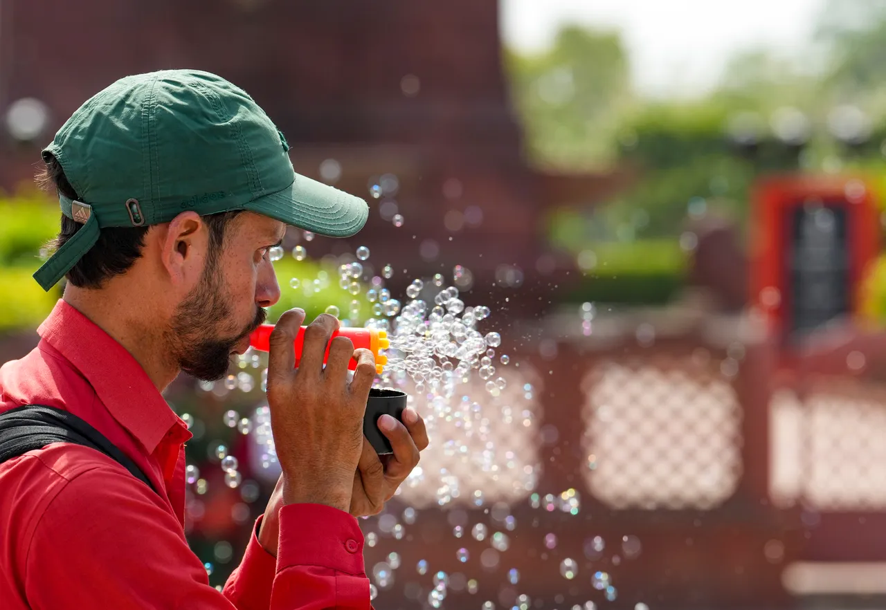 A vendor blows soap bubbles to attract customers on a hot summer day, in New Delhi