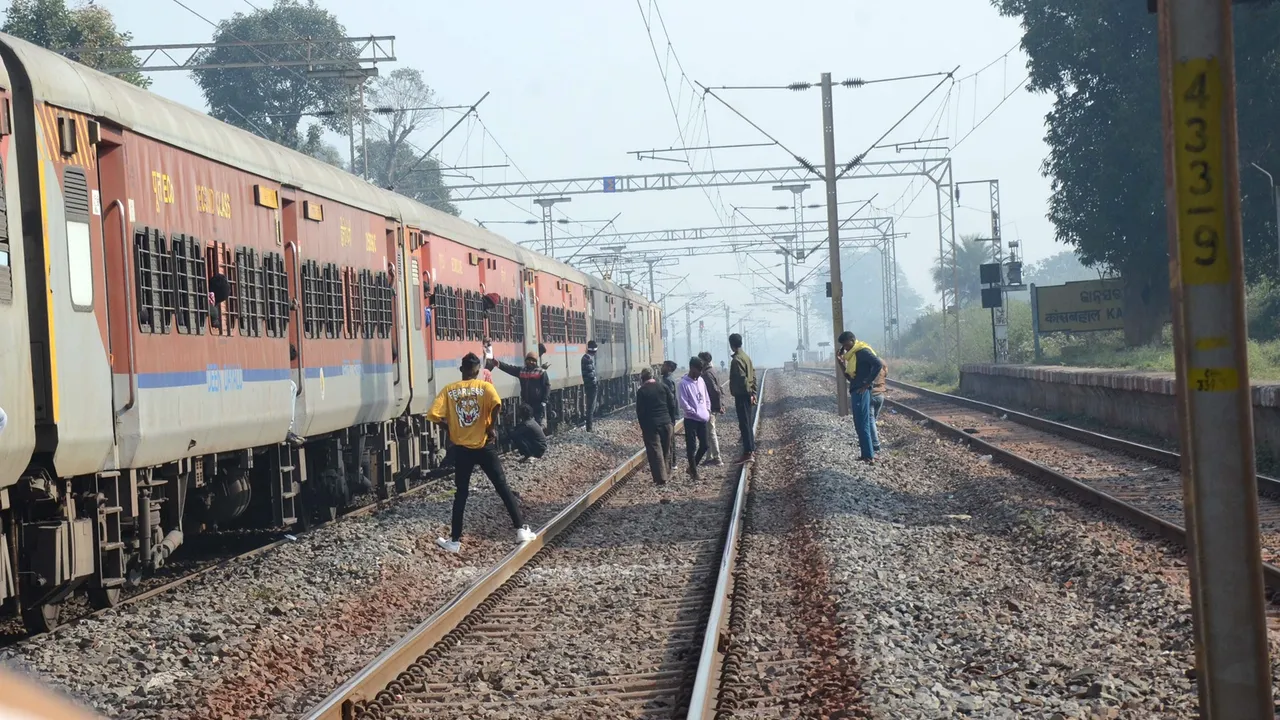 Passengers wait on tracks following a disruption in train services on the Howrah-Mumbai route