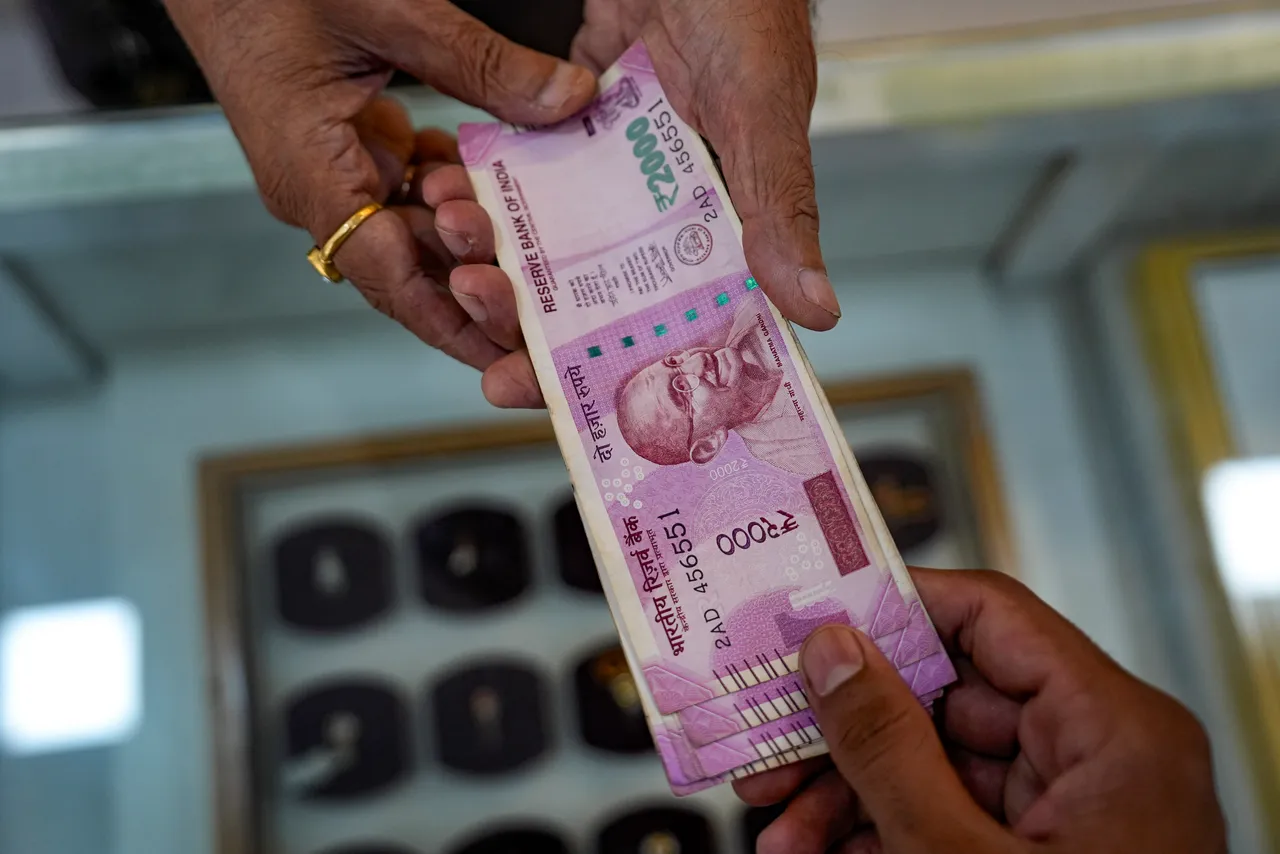 A customer gives Rs 2,000 rupee currency notes to the shopkeeper at a jewellery shop in Mumbai