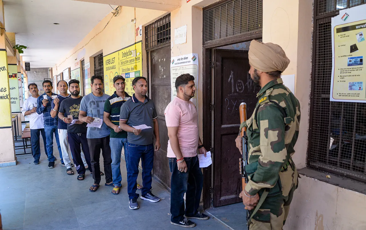 People wait in queue at a polling station to cast their votes for Jalandhar Lok Sabha by-election seat, in Jalandhar