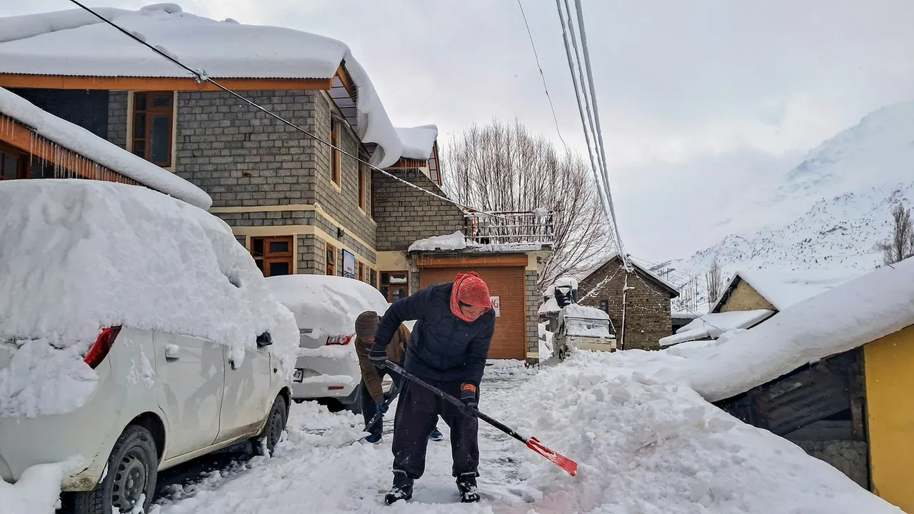 Workers remove snow at a locality at Keylong after fresh snowfall, in Lahaul and Spiti district