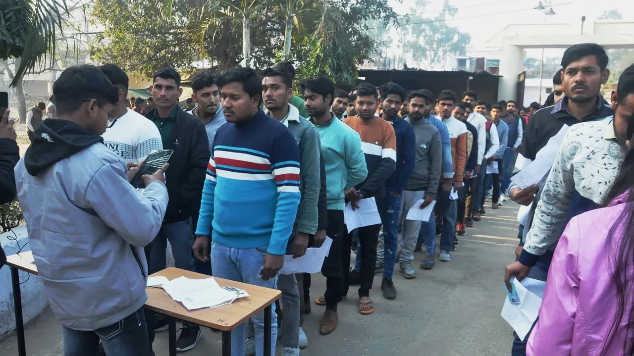 Candidates wait outside an examination centre to appear in the UP Police Constable recruitment exam, in Moradabad