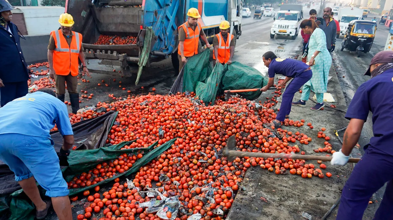 Workers clean a road after a truck carrying tomatoes overturned near Patlipada bridge, in Thane