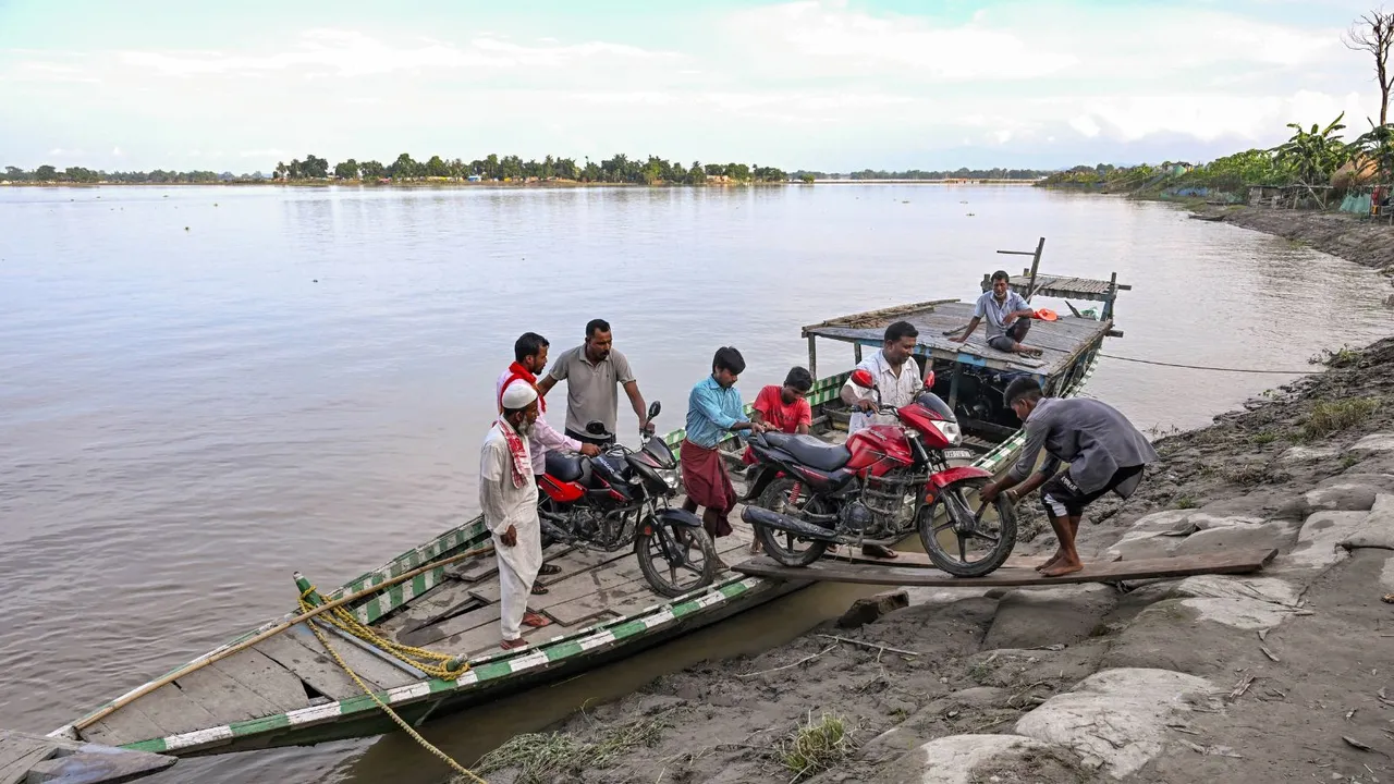 People move their motorcycles on a boat amid floods, in Morigaon district